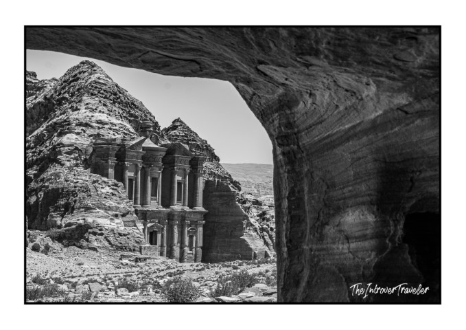 Ad Deir Monastery in Petra Jordan, framed through a rocky cave opening, black and white