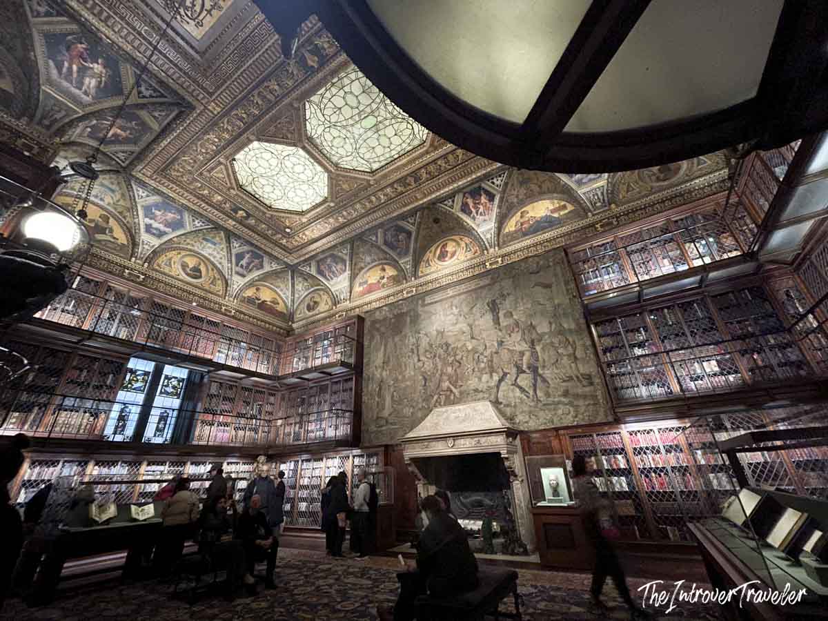 Ornate painted ceiling and three-story bookshelves inside the Morgan Library West Room, New York