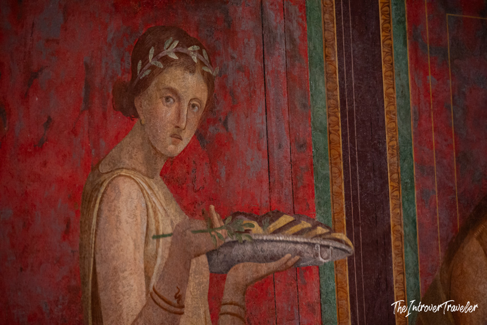 Ancient Roman fresco from Pompeii showing a woman with laurel wreath carrying an offering tray