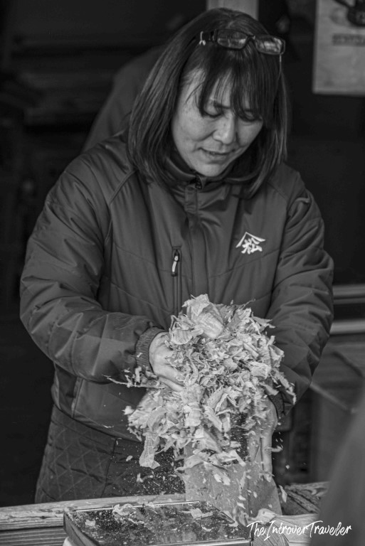 Woman at Tsukiji fish market Tokyo handling fresh shaved bonito flakes at a market stall