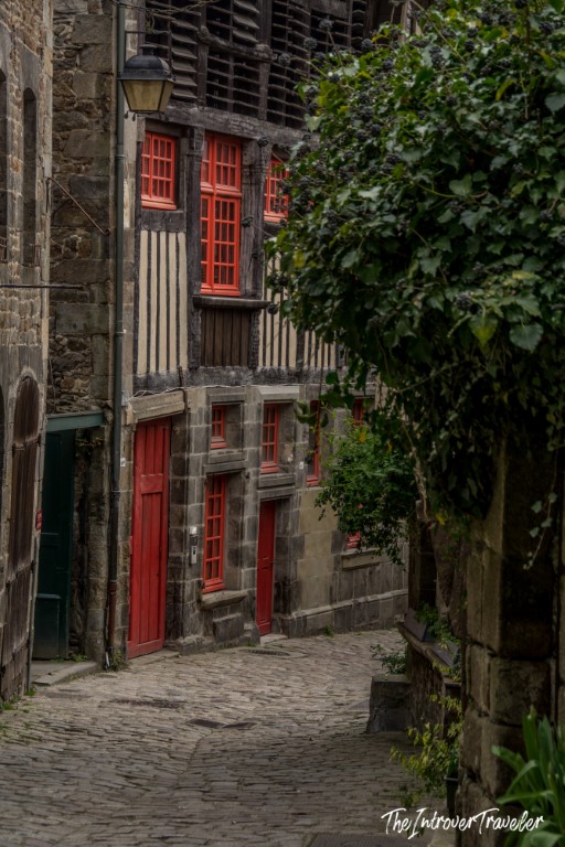 Cobblestone alley in Dinan with half-timbered medieval buildings and red windows, Brittany France