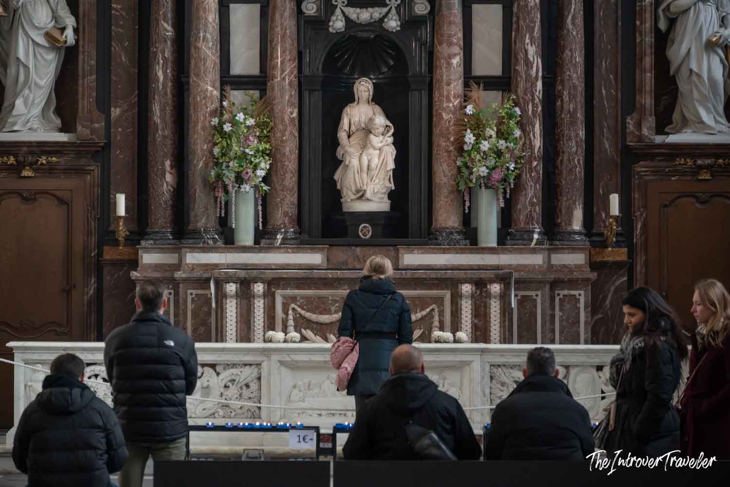 Visitors viewing Michelangelo's Madonna of Bruges at the marble altar in the Church of Our Lady