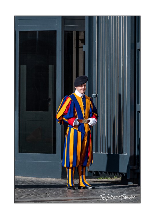 Papal Swiss Guard in colorful striped uniform standing at a Vatican entrance gate