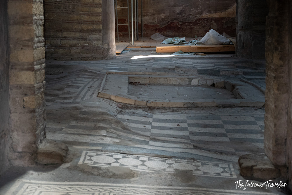 Ancient Roman mosaic floor with impluvium basin inside a Herculaneum house under restoration