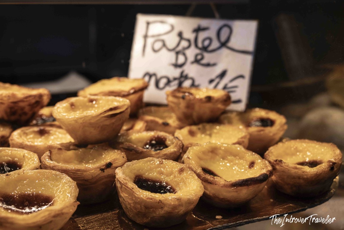 Freshly baked pasteis de nata on a tray, labeled with a handwritten sign priced at 1 euro in Porto