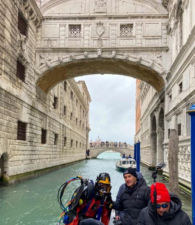 Diver and crew on a boat passing under the Bridge of Sighs, Venice canal