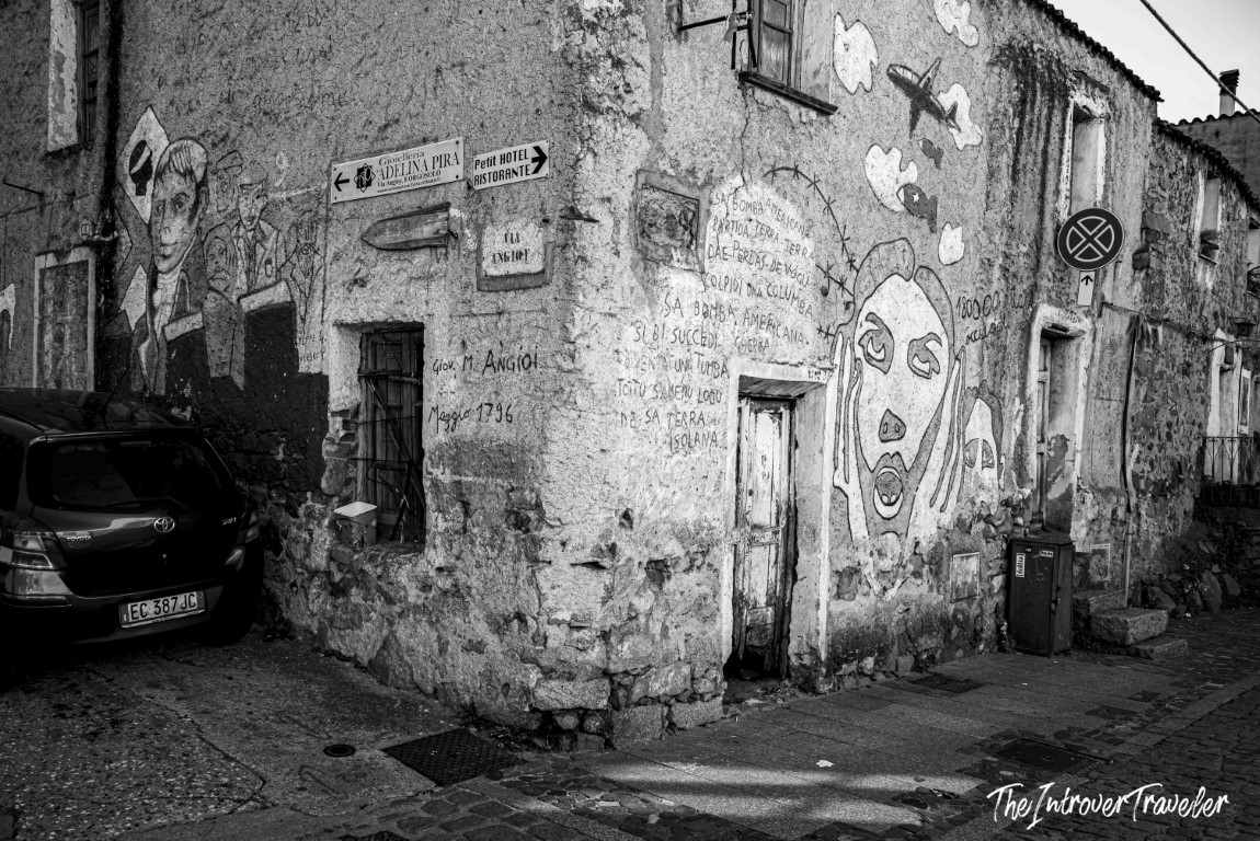 Street corner in Orgosolo, Sardinia, covered in political murals with Sardinian text and painted faces