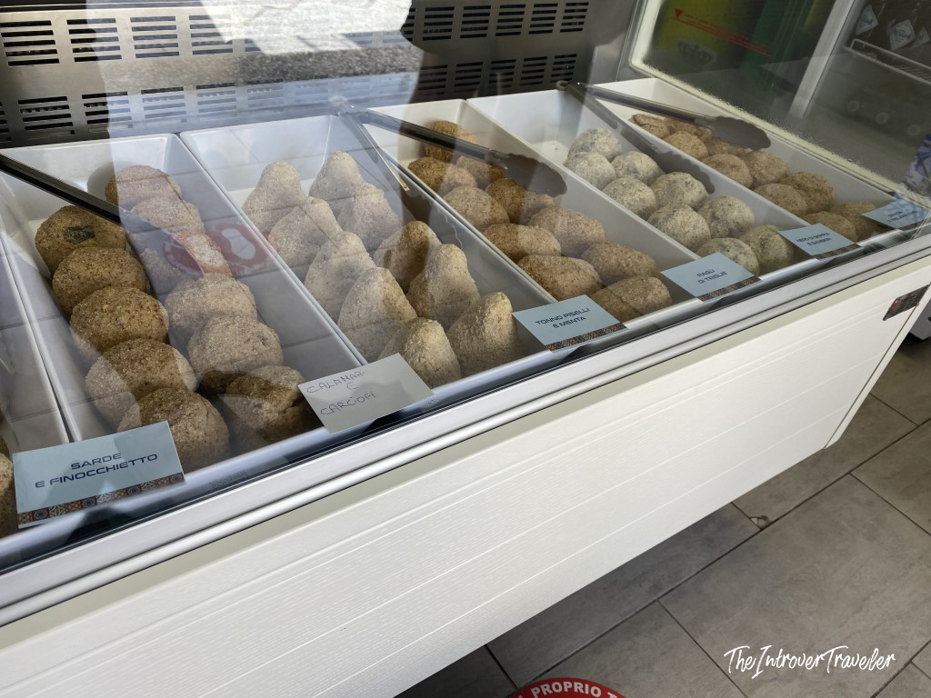 Arancini display case in Favignana with flavors like sarde e finocchietto and calamari e carciofi