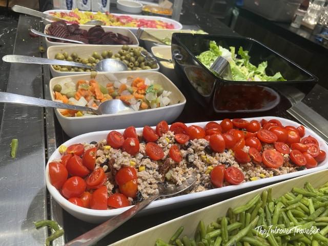 Fresh salad bar at Plaza Premium Lounge Fiumicino, with cherry tomatoes, olives, greens, and mixed vegetables