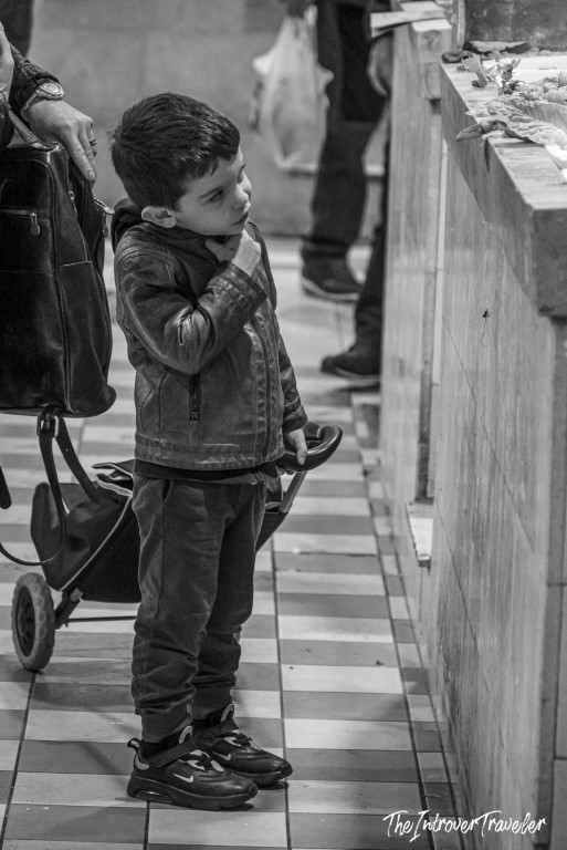 Young boy curiously peering over a fish market counter, capturing everyday life at a coastal city market