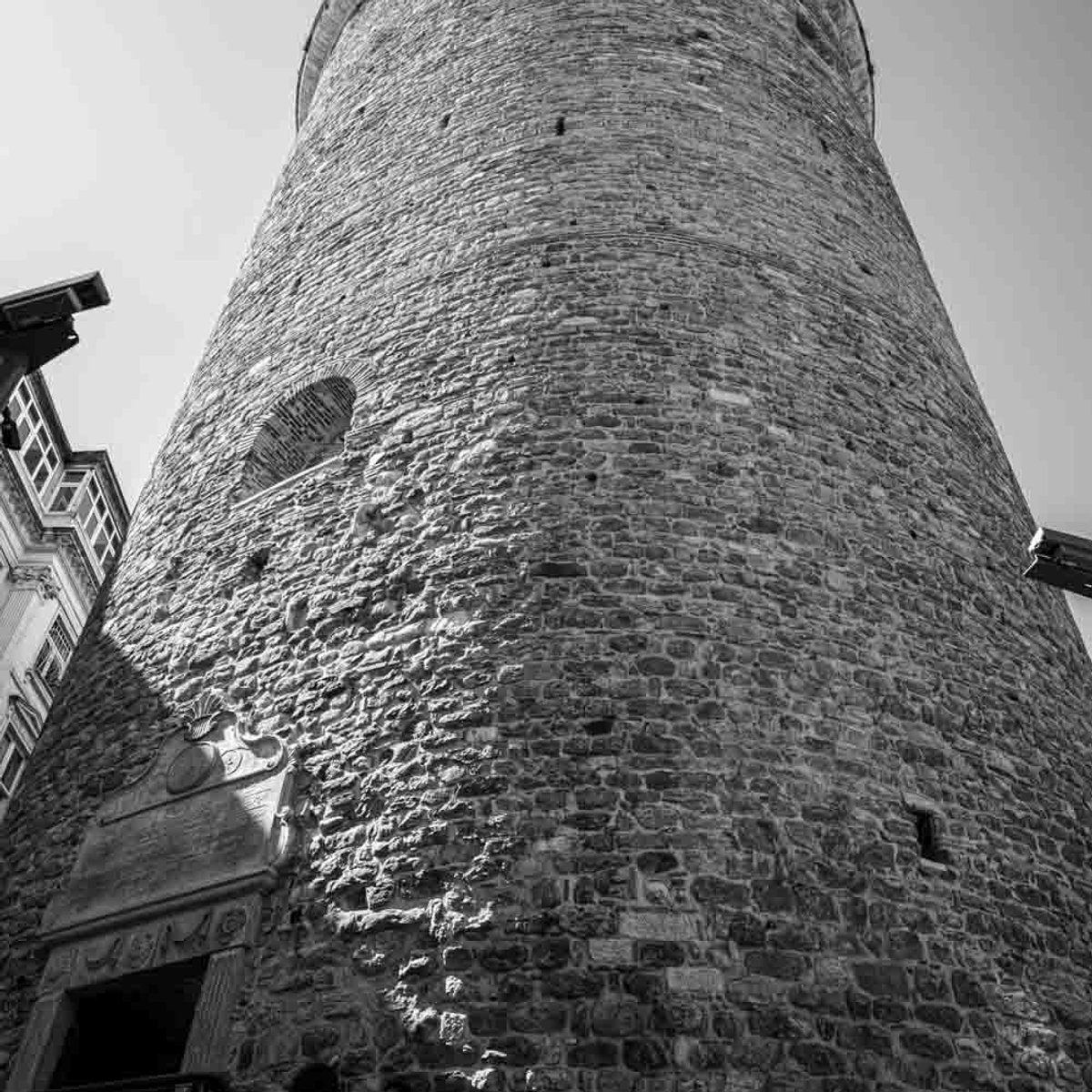 Galata Tower base viewed from street level, black and white, Istanbul landmark