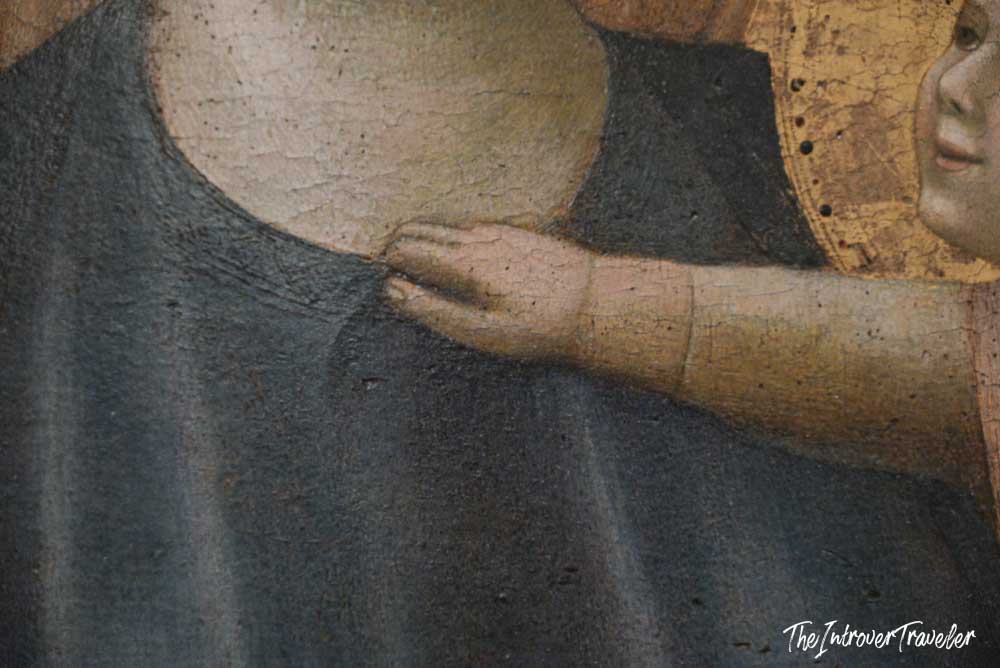 Close-up of a delicate hand and gilded halo in a Renaissance painting at the Uffizi Gallery, Florence