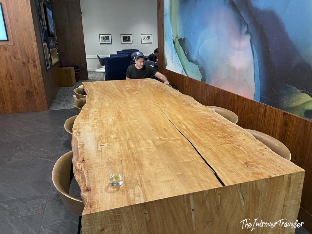 Large live-edge wood communal table inside the Centurion Lounge at LGA airport