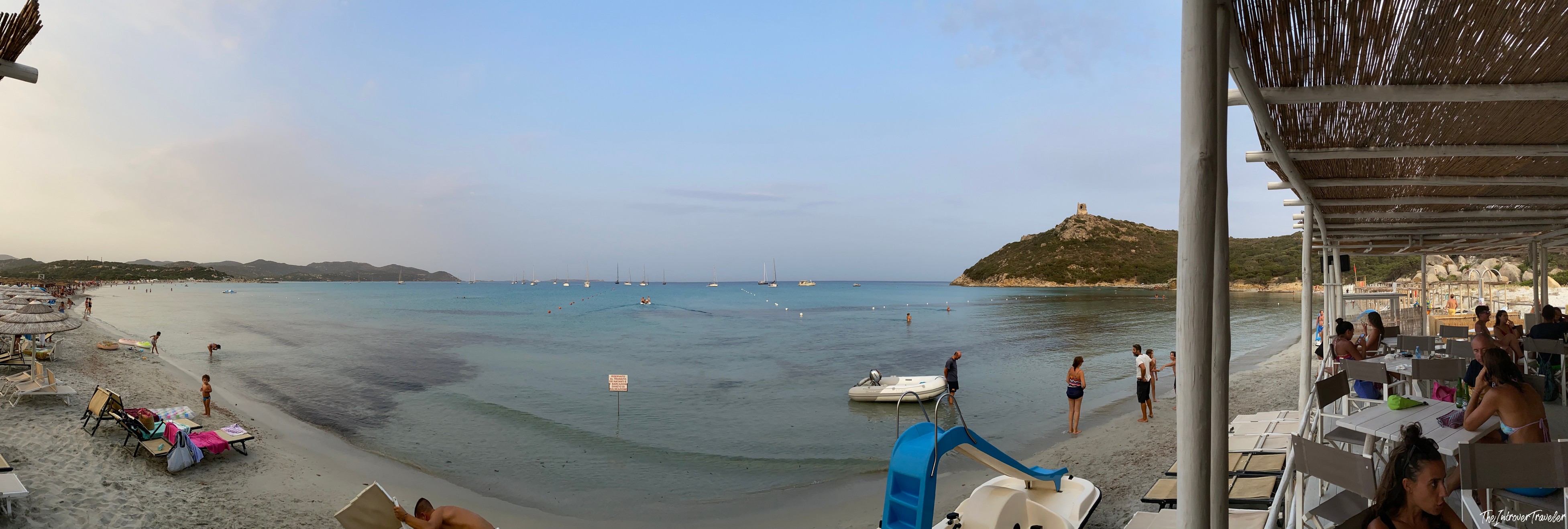 Panoramic view of a south Sardinia beach bay with a Spanish watchtower on the hill and sailboats anchored offshore
