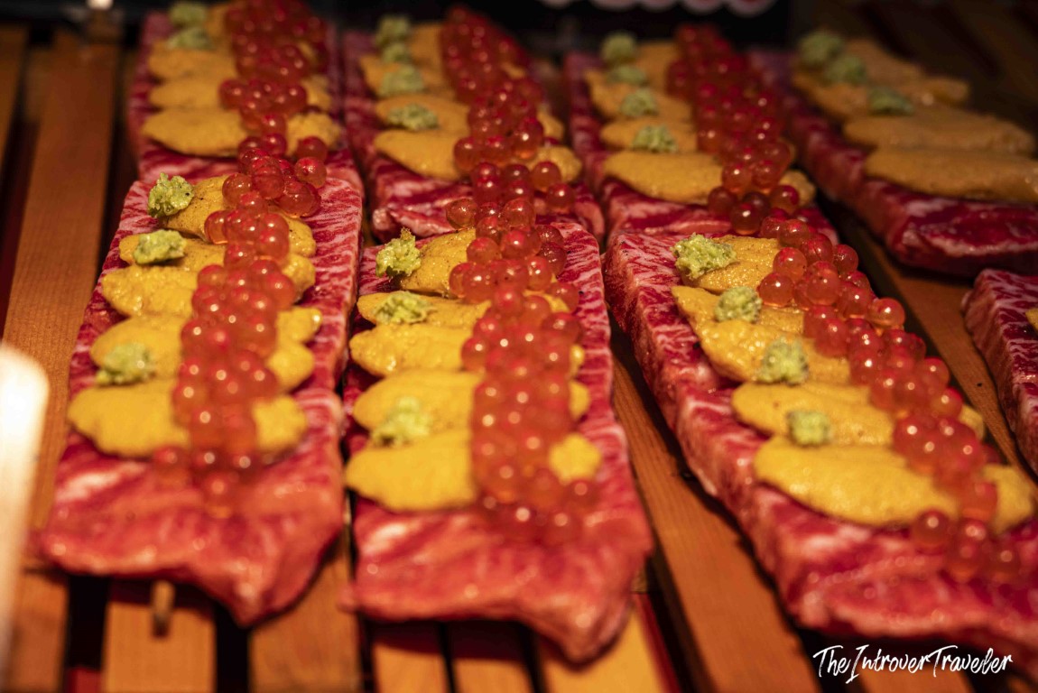Raw wagyu beef slices topped with uni, ikura salmon roe, and wasabi at Tsukiji fish market Tokyo