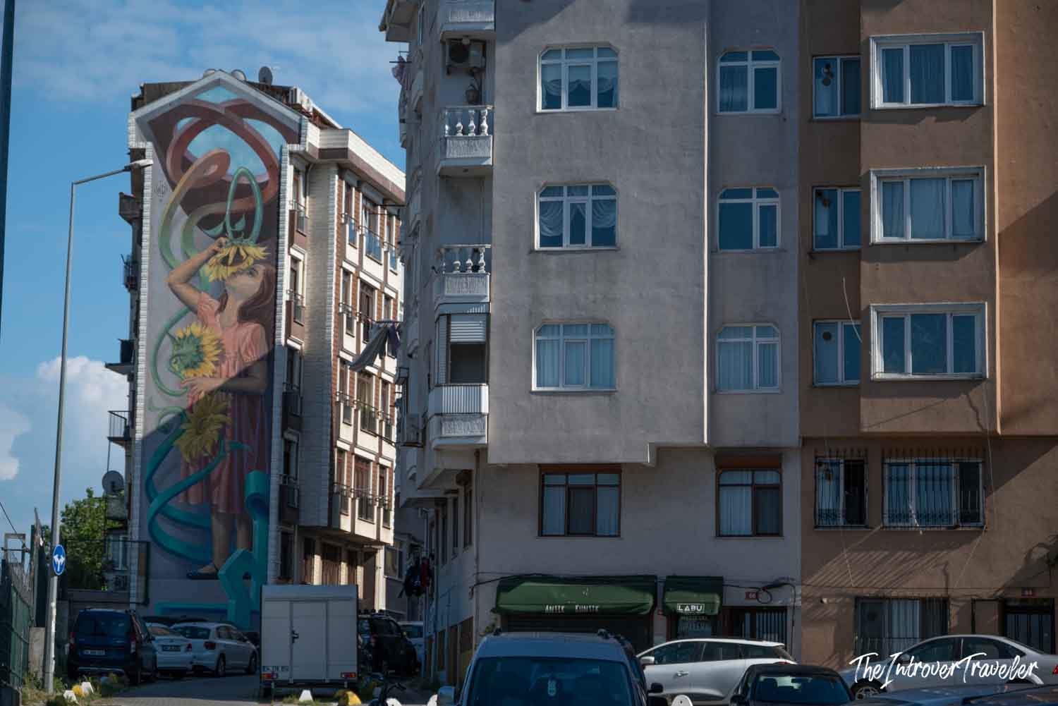 Large street art mural of a girl holding sunflowers on a residential building in Kadıköy, Istanbul