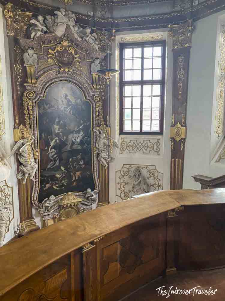 Ornate Baroque chapel interior at the Belvedere Palace Vienna, with gilded altar painting and carved wooden pews