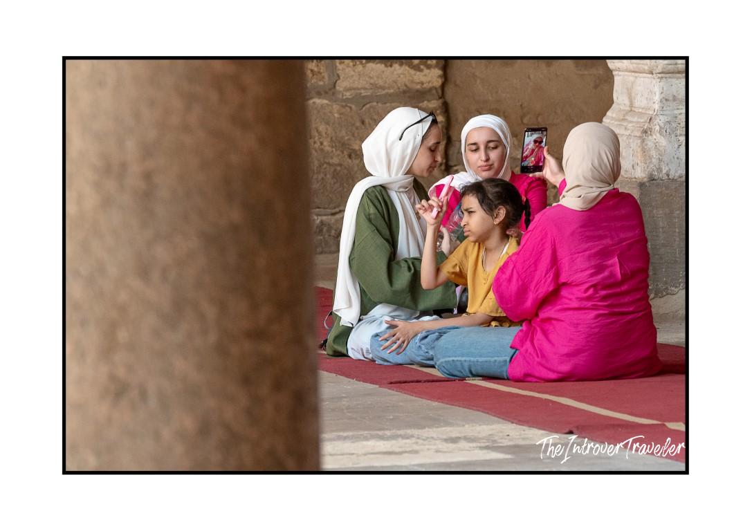 Muslim women and a young girl resting on a prayer mat inside a Cairo mosque, Egypt
