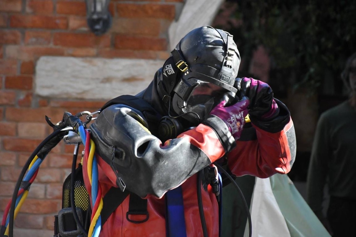 Venice canal diver in full dry suit and breathing mask adjusting gear before a canal dive