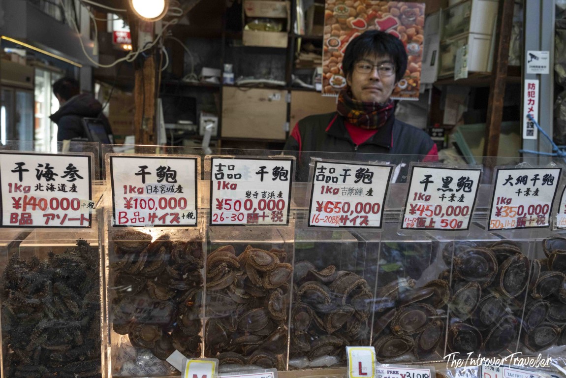 Vendor at Tsukiji fish market Tokyo selling dried abalone and sea cucumber with yen price tags