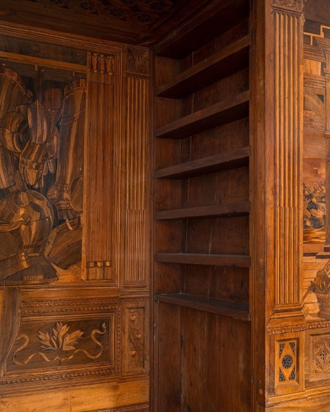 Intricately inlaid wooden walls and built-in shelves inside the Studiolo of Federico da Montefeltro, Urbino