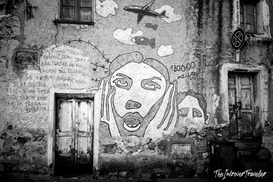 Political mural in Orgosolo, Sardinia, depicting screaming faces protesting American military presence in Sardinia