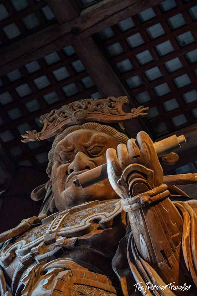 Massive wooden guardian statue inside Todaiji Temple, Nara, viewed from below showing fierce expression and armor detail
