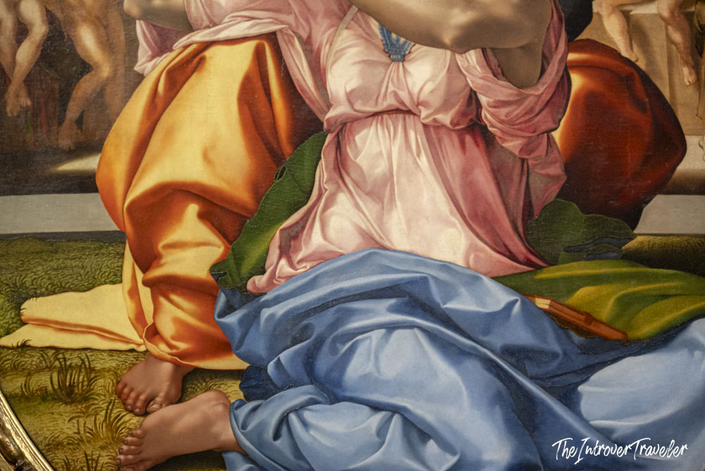Close-up of richly draped figures in pink, orange, and blue in a Renaissance painting at the Uffizi Gallery Florence