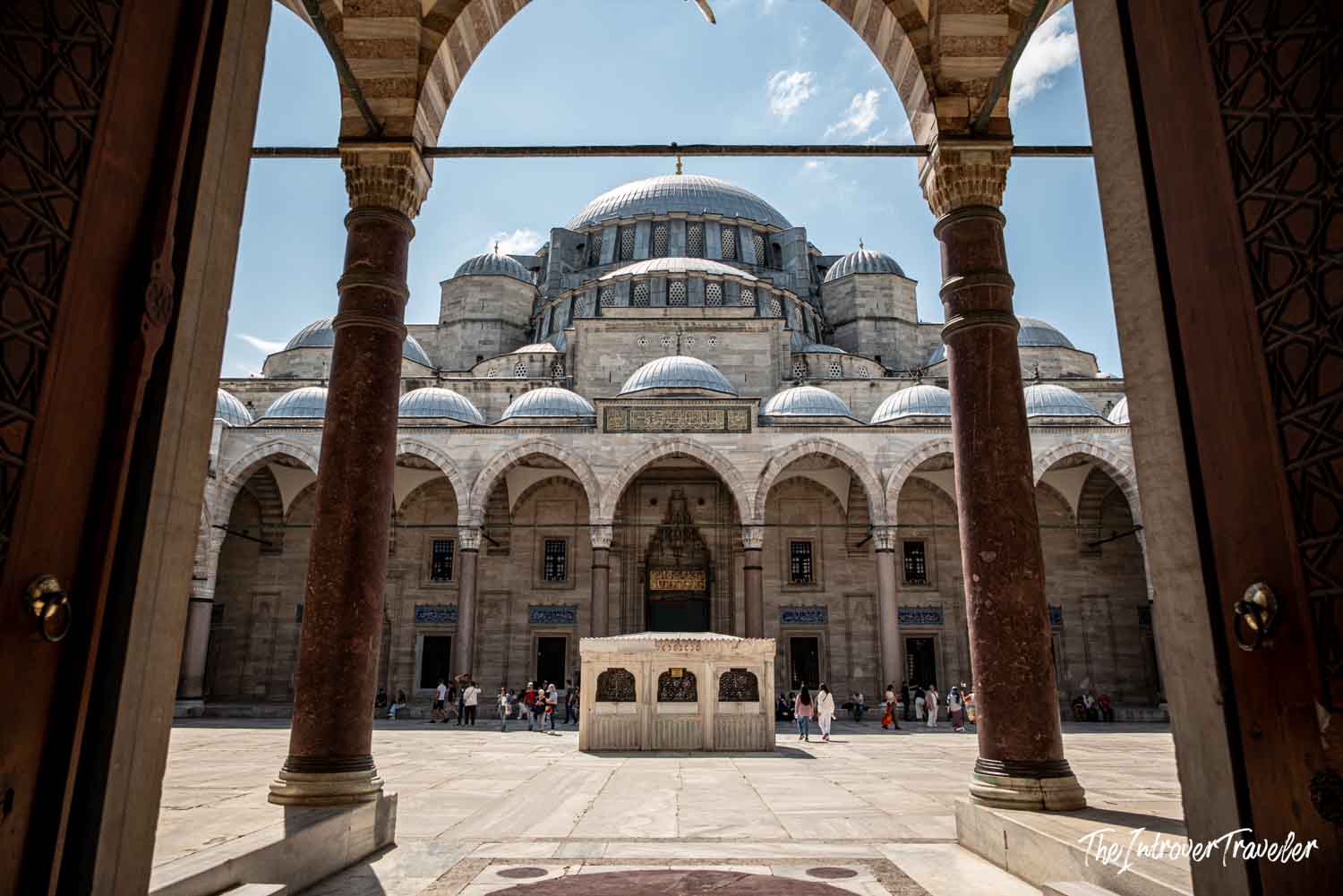 Süleymaniye Mosque courtyard in Istanbul, with cascading domes and ornate stone arches framing the entrance