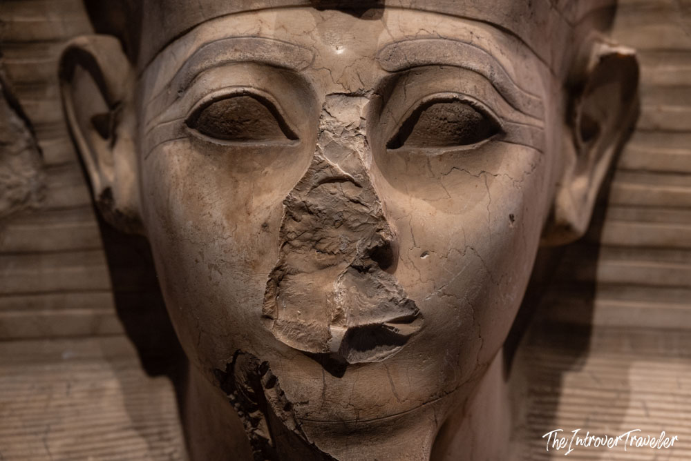 Close-up of a damaged ancient Egyptian pharaoh statue face at the Grand Egyptian Museum, Cairo