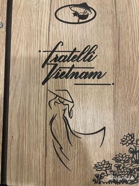 Wooden menu cover of Fratelli Vietnam restaurant in Bologna, with engraved logo and Vietnamese woman silhouette