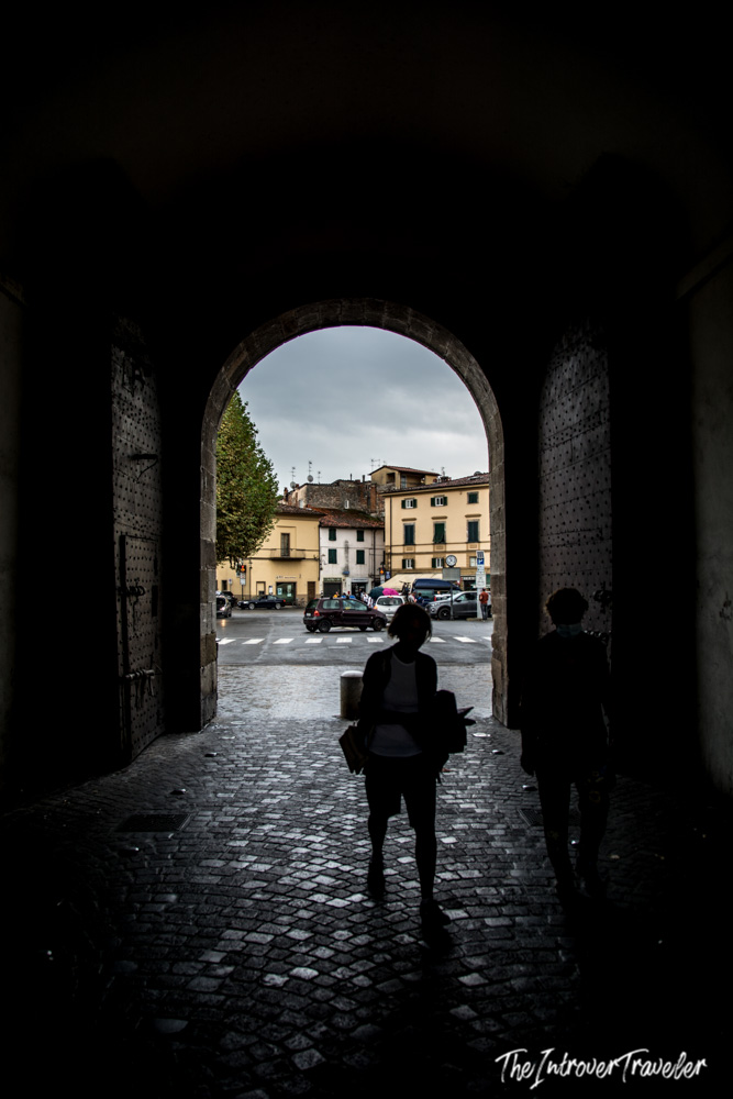 Silhouetted traveler passing through a medieval gate in Lucca's ancient city walls, Tuscany