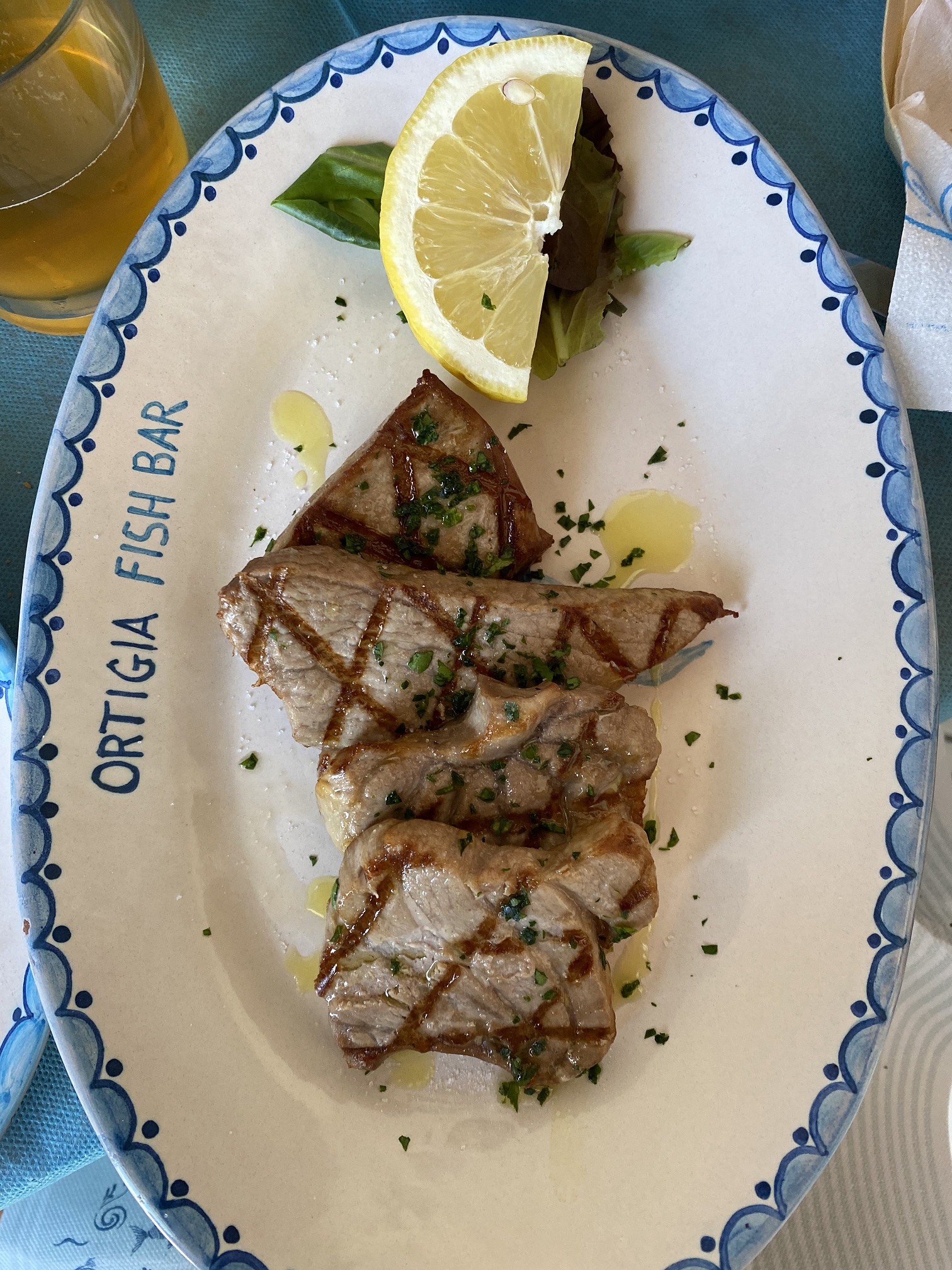 Grilled tuna porchetta with herbs and lemon on a ceramic plate at Ortigia Fish Bar, Syracuse