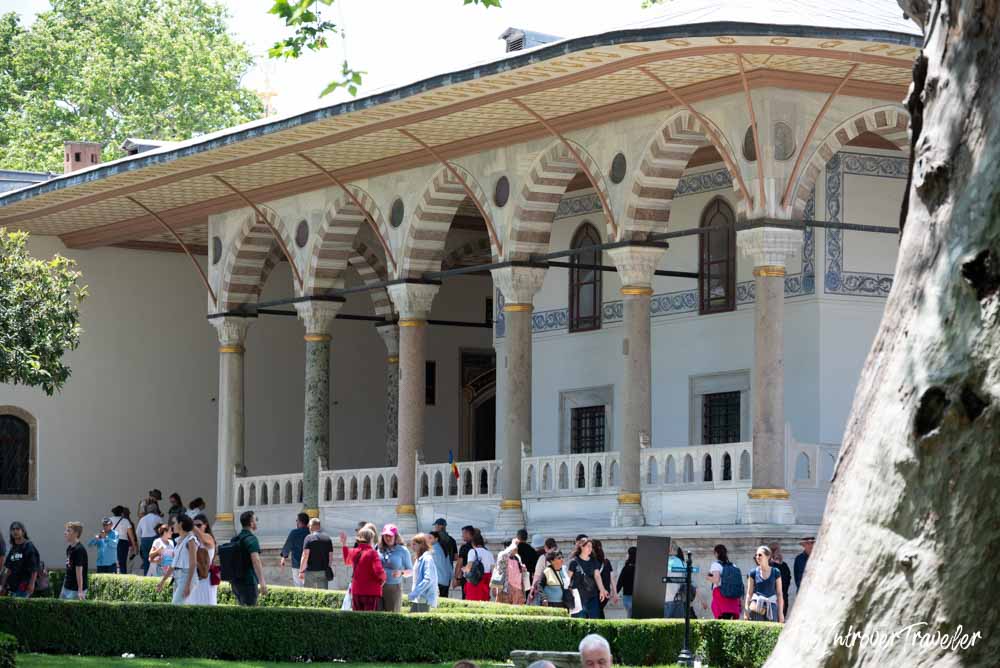 Crowds of tourists gathered outside the ornate colonnaded portico of Topkapi Palace, Istanbul