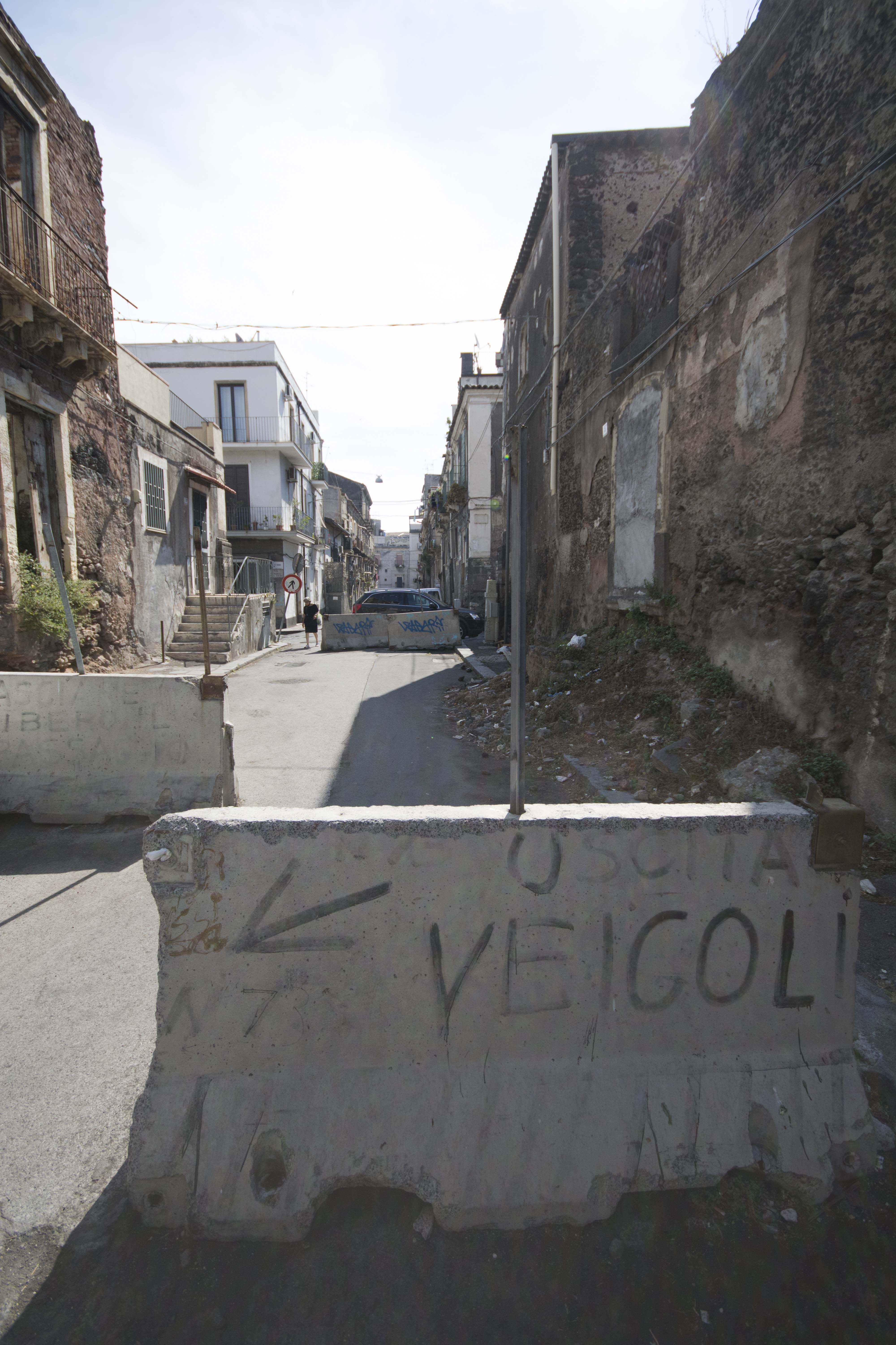 Concrete barrier reading "Veicoli" on a rundown Catania street, showing the city's neglected outskirts