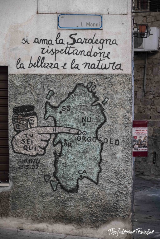 Orgosolo mural on Via L. Monni with map of Sardinia and Italian text praising the island's beauty