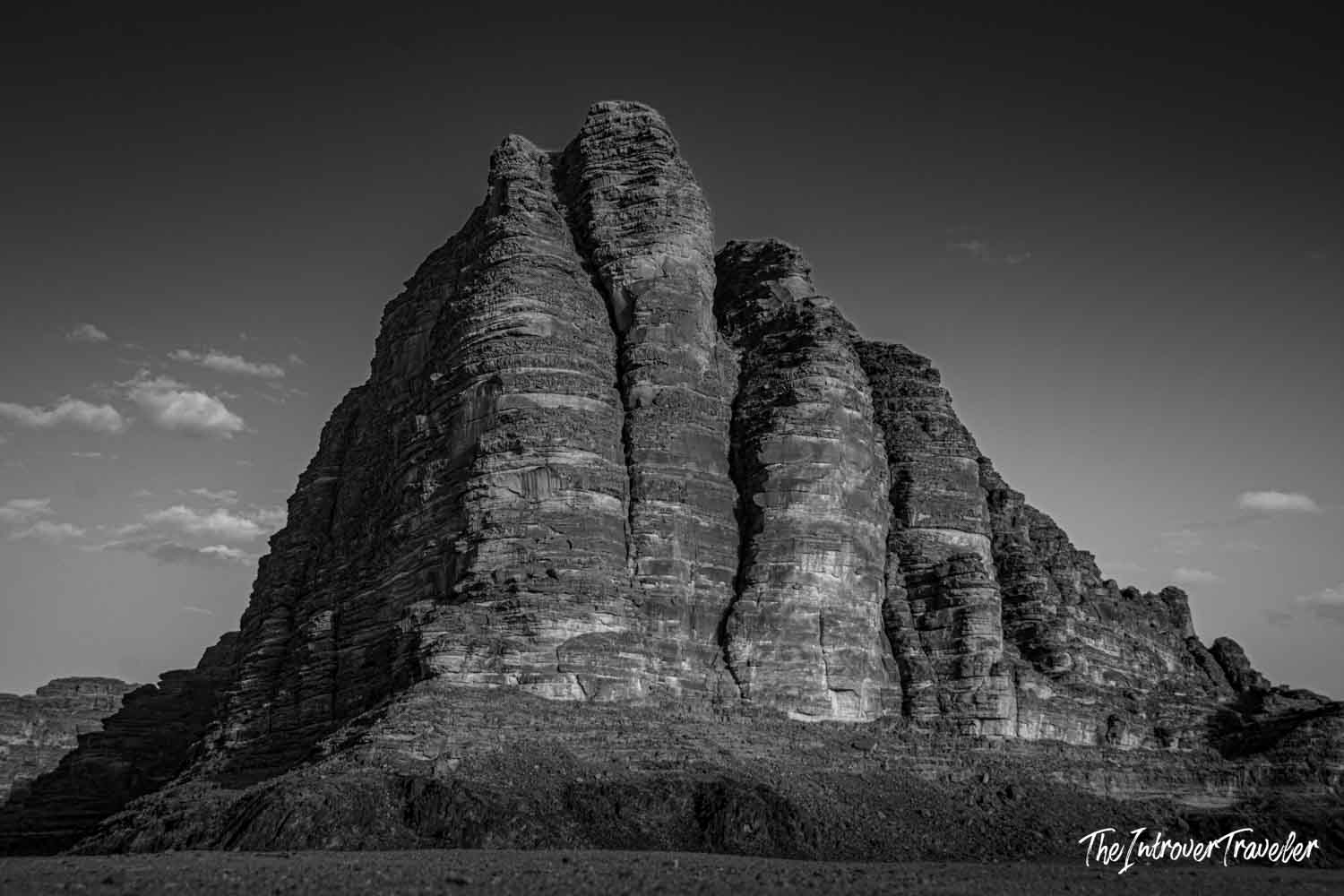 Dramatic sandstone rock formation rising above Wadi Rum desert, Jordan, captured in black and white