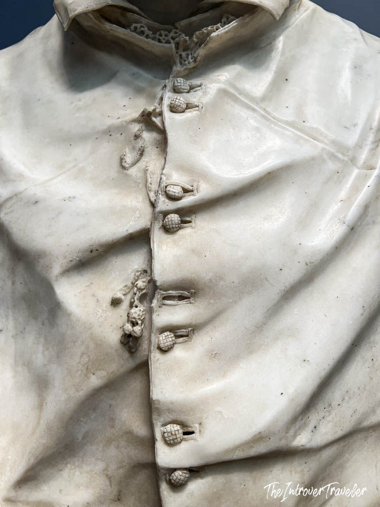 Close-up of intricately carved marble buttons and fabric folds on a bust at the Met