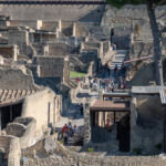 Aerial view of Herculaneum excavations showing ancient Roman ruins and tourists walking the site pathways