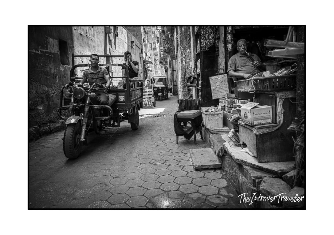 Narrow Cairo alley with a cargo tricycle, street vendor, and daily life in Egypt