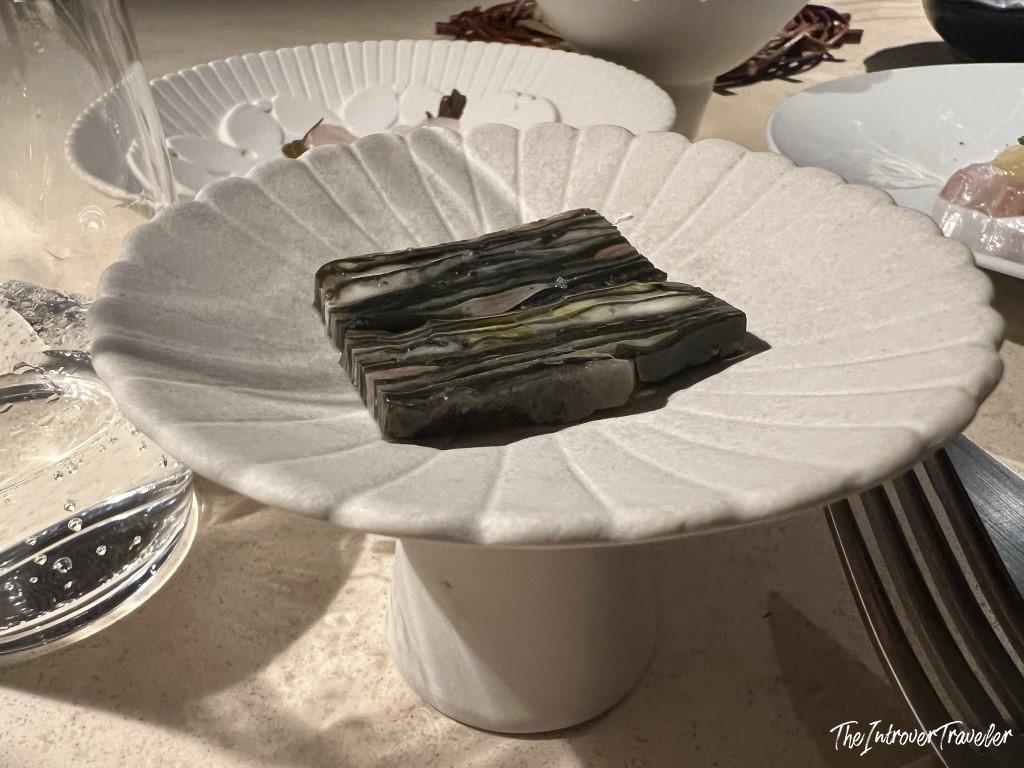 Layered fish terrine on a scallop-shaped pedestal plate at Trattoria Da Lucio, Rimini