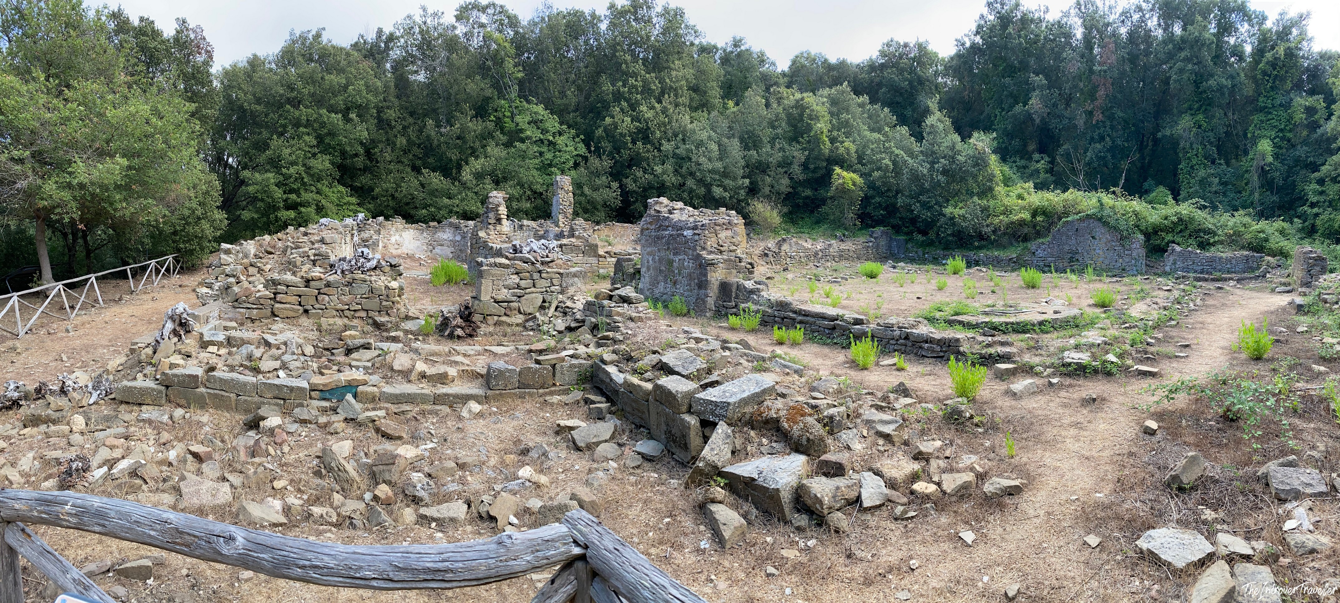 Panoramic view of ancient stone ruins surrounded by dense woodland along the Cala Moresca trekking trail, Sardinia