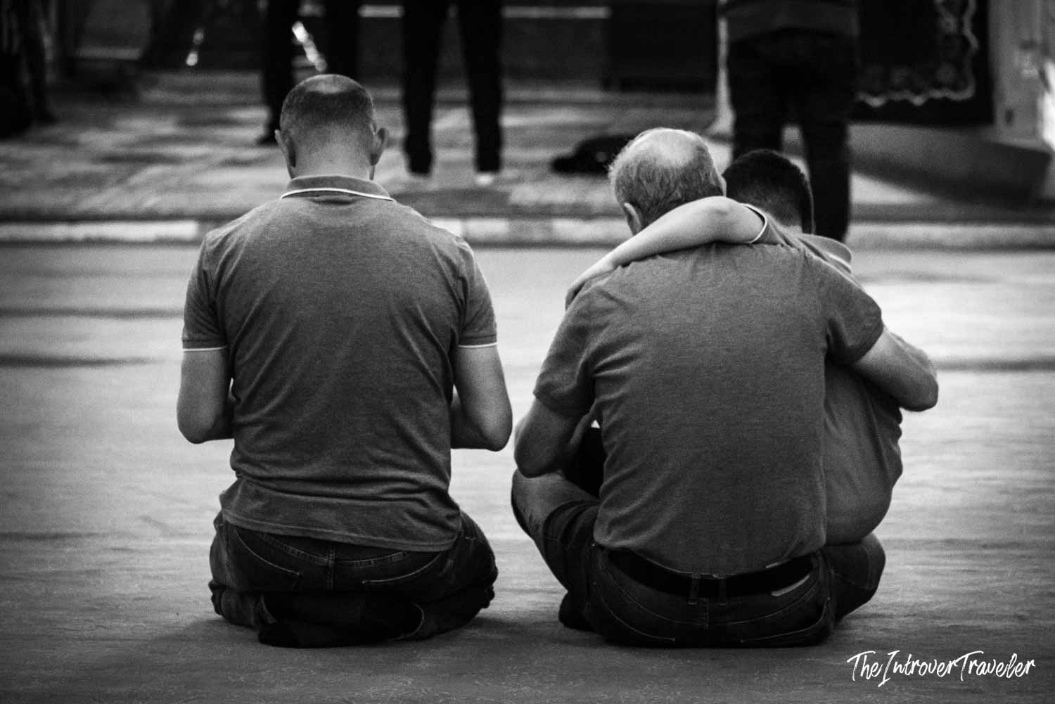 Men kneeling in prayer on the floor of a mosque in Istanbul, seen from behind