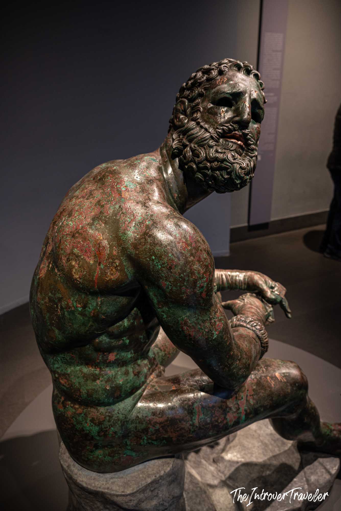 Boxer at Rest ancient Greek bronze statue, rear view showing muscular back and curly beard