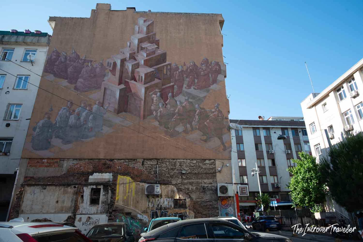 Large street art mural on a building wall in Kadıköy, Istanbul, depicting robed figures around a tower