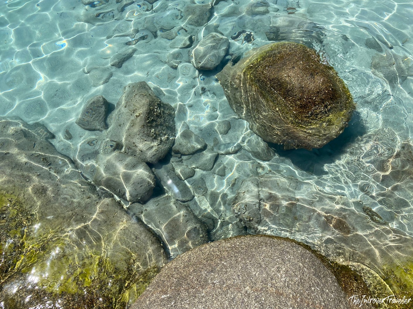 Crystal clear shallow water over smooth granite boulders at a south Sardinia beach