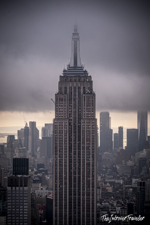 Empire State Building towering over Manhattan skyline on a moody overcast day, viewed from Top of the Rock