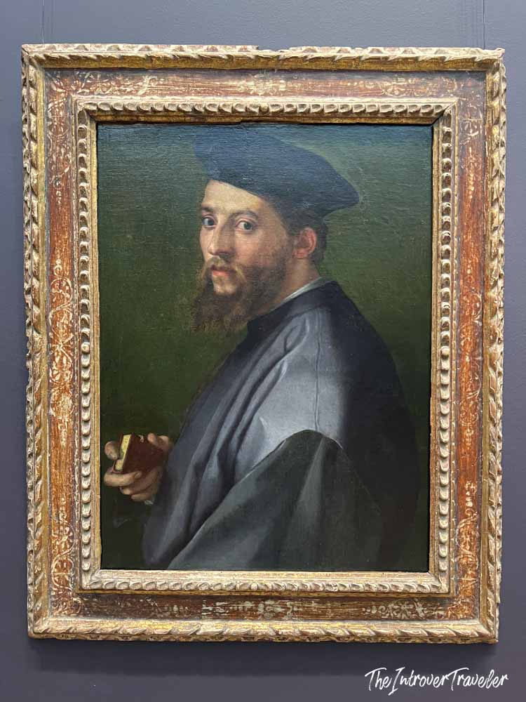 Renaissance portrait painting at the Met, bearded man in blue beret holding a book, ornate gilded frame