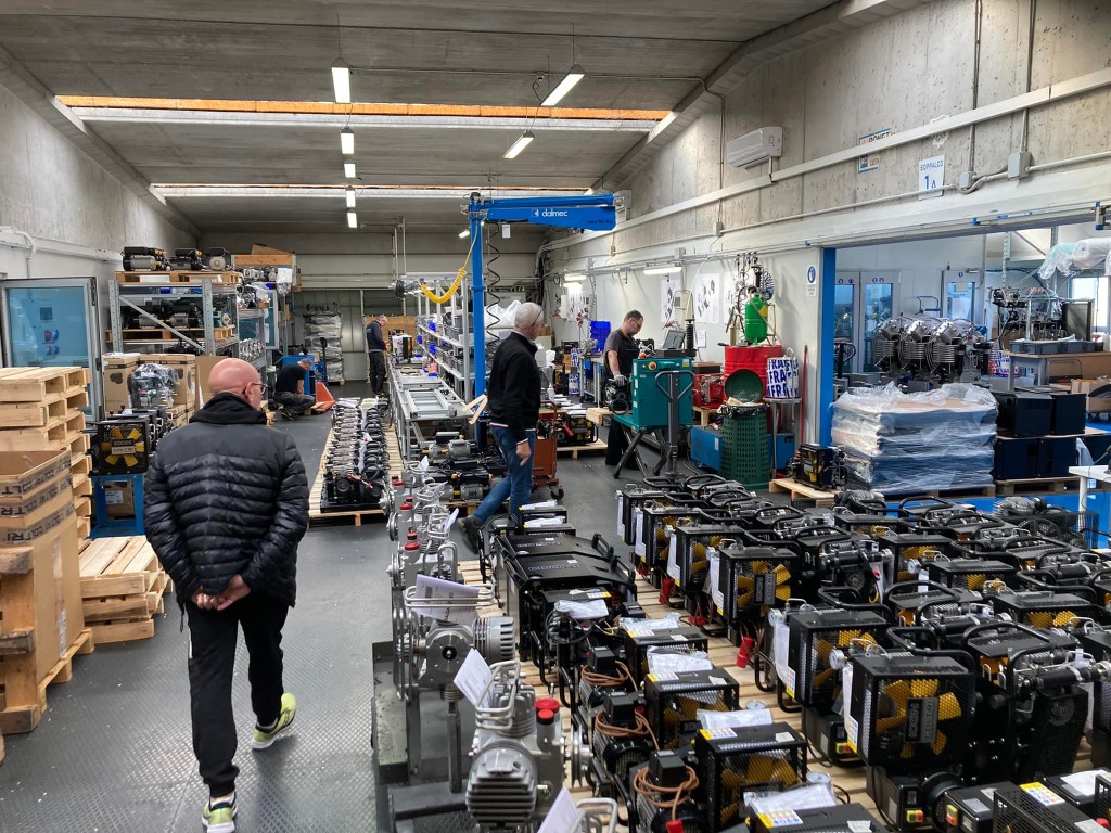 Venice canal diving equipment assembly line, workers inspecting compressors and gear in a factory warehouse