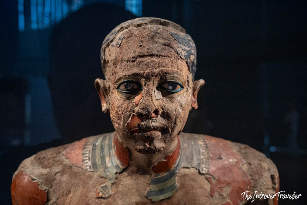 Ancient Egyptian painted wooden funerary statue with kohl-lined eyes, on display at the Grand Egyptian Museum in Cairo
